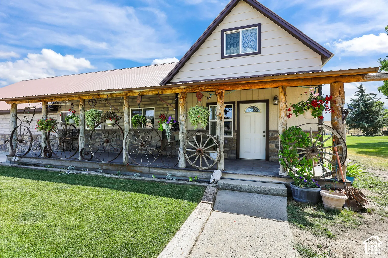 Exterior facade featuring stone veneer, horizontal siding, and a covered porch supported by rustic log columns with a metal roof