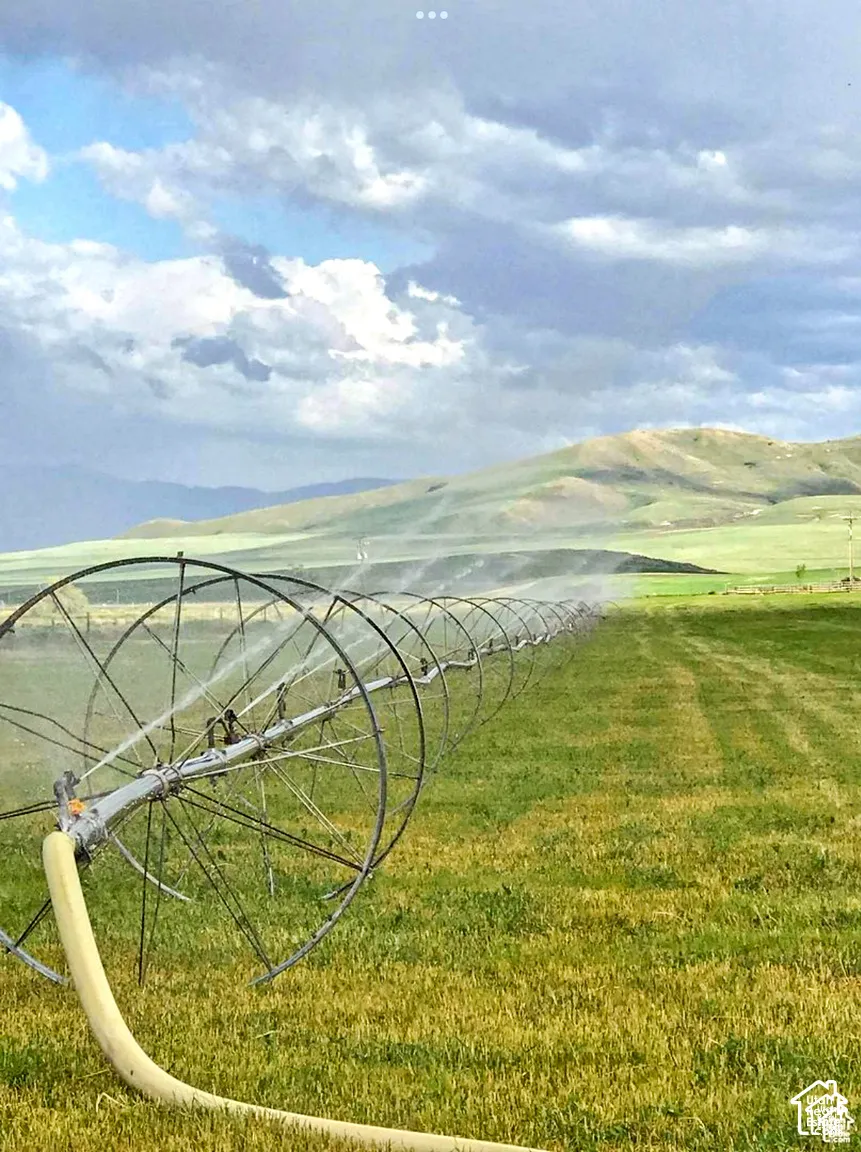 Expansive acreage featuring a wheel line irrigation system, rolling pastureland, and mountain backdrop