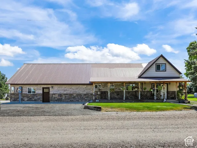 Rustic exterior featuring natural stone veneer, horizontal siding, a metal roof, and a covered porch supported by timber posts