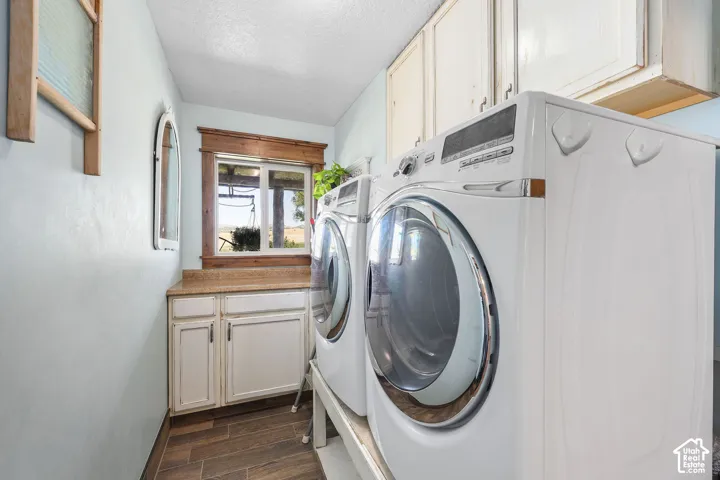 Laundry room featuring wood-finish tile flooring, shaker-style cabinetry, solid-surface countertops, and wood-trimmed window casing