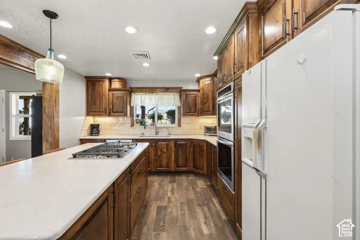 Kitchen featuring stained wood cabinetry, quartz countertops, a center island with a built-in gas cooktop, recessed lighting, and wood-finish flooring