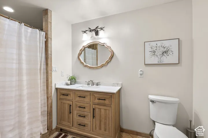 Bathroom featuring a wood-finish vanity with a stone-top integrated sink, matte black hardware, and an ornate wall mirror illuminated by a three-light fixture