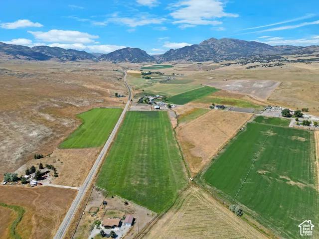 Aerial perspective featuring expansive acreage, irrigated agricultural fields, and prominent mountain backdrops