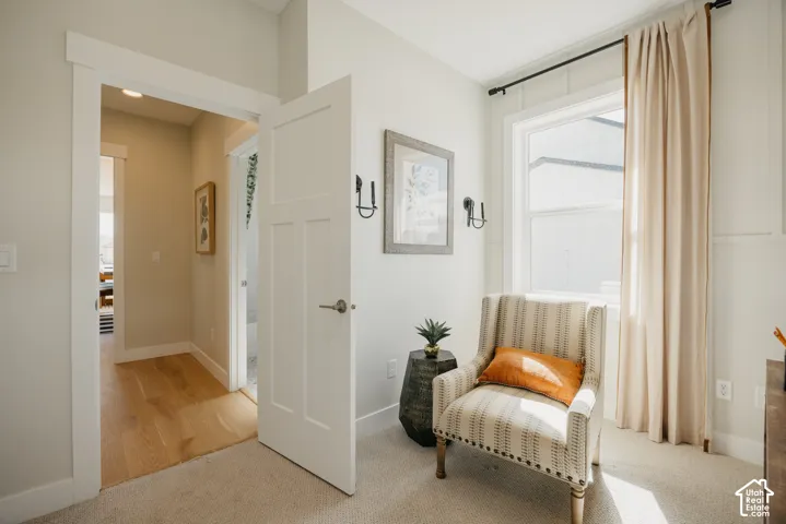 Neutral interior featuring wall-mounted black sconce lighting, board and batten wall detailing, high-profile door casing, shaker-style door, and wood-finish flooring