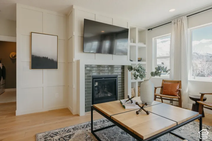 Custom grid-paneled accent wall featuring an integrated fireplace with glazed tile surround, recessed display shelving, and light-toned wood-finish flooring