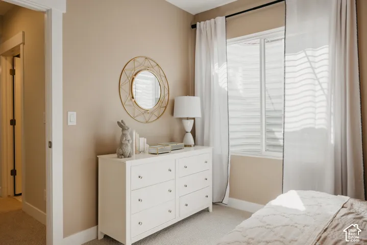 Neutral-toned room featuring wall-to-wall carpeting, a sliding window with a horizontal grid, and a door frame with crisp white casing