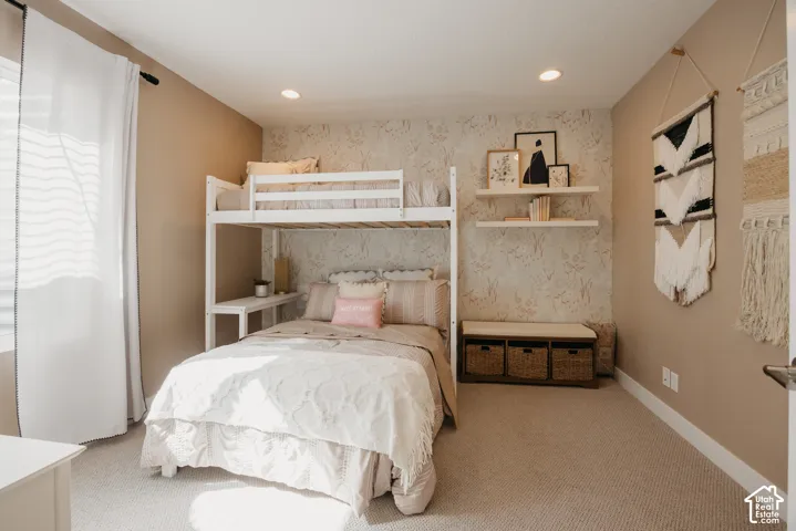 Bedroom featuring patterned wallpaper, neutral carpeting, recessed lighting, and dual wall-mounted floating shelves