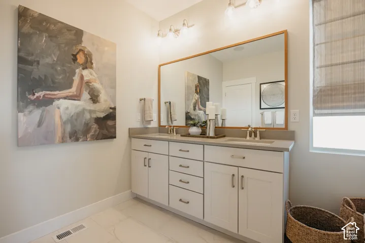 Double vanity featuring shaker-style cabinetry, solid-surface countertop with dual integrated sinks, brushed-finish hardware, and a large wood-framed mirror