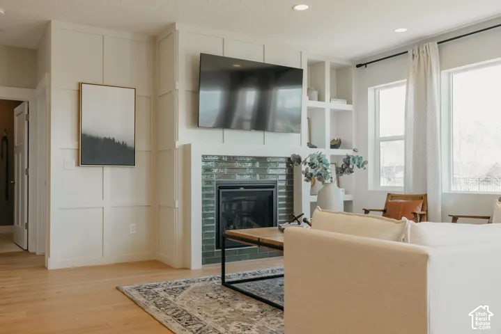 Fireplace surround featuring green glossy tile, floor-to-ceiling grid-patterned wainscoting, and recessed built-in shelving