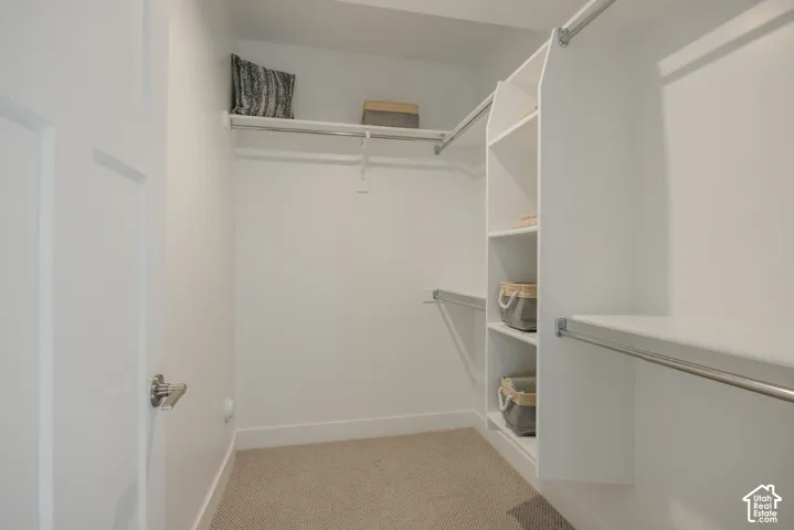Walk-in closet featuring white built-in shelving, integrated tiered storage, and dual-level hanging rods