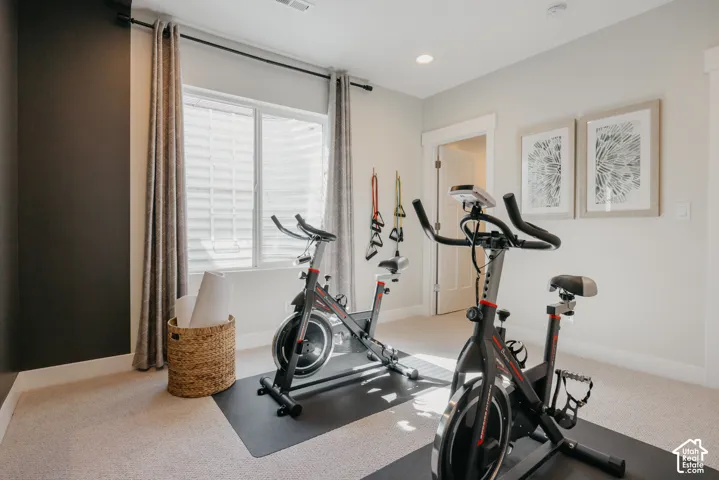 Neutral-toned room featuring a high-contrast charcoal accent wall, neutral carpeting, recessed ceiling lighting, and a large window with white window trim
