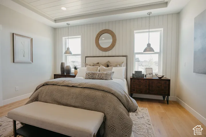 Vertical shiplap wall paneling, recessed tray ceiling with shiplap detailing, light-toned wood-finish flooring, and dual hanging metal pendant lights