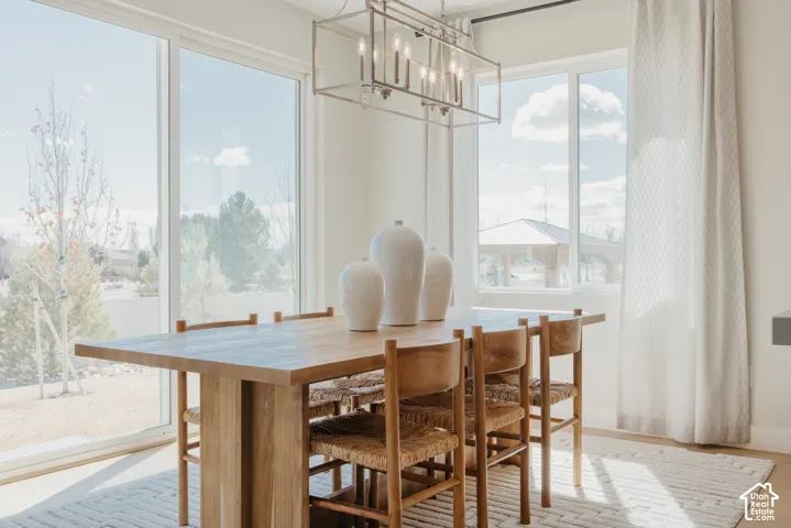 Rectangular, metal-frame chandelier with multi-light fixture, expansive sliding glass door, large-format window, and neutral-toned wall finish