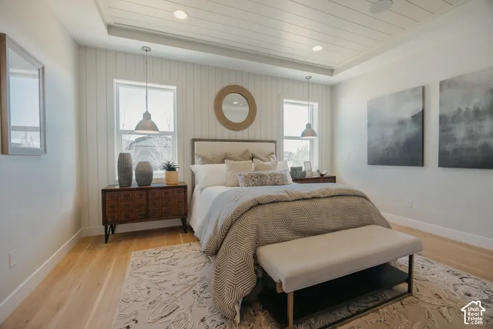 Tray ceiling with shiplap detailing, vertical board-and-batten wall paneling, light-tone wood-finish flooring, and recessed lighting