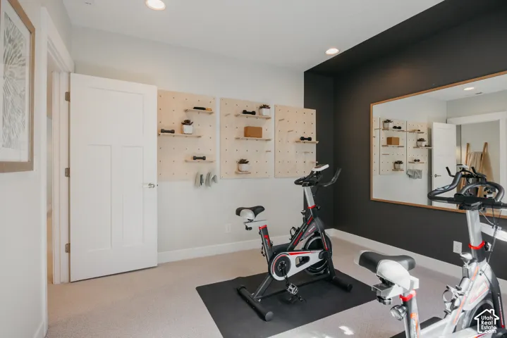 Room featuring a charcoal accent wall, recessed lighting, wall-mounted light-toned wooden pegboard shelving, and a large wall-mounted mirror with a thin wood frame