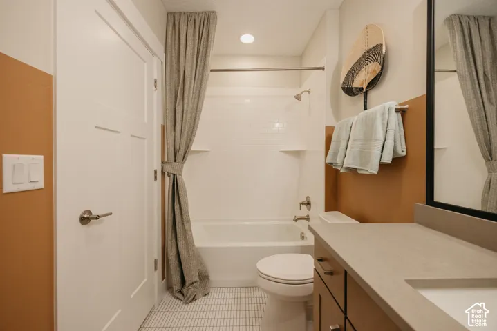 Bathroom featuring a vanity with a solid-surface countertop, an integrated rectangular sink, a tub-shower combination with white subway-style wall tile, and small-format tile flooring