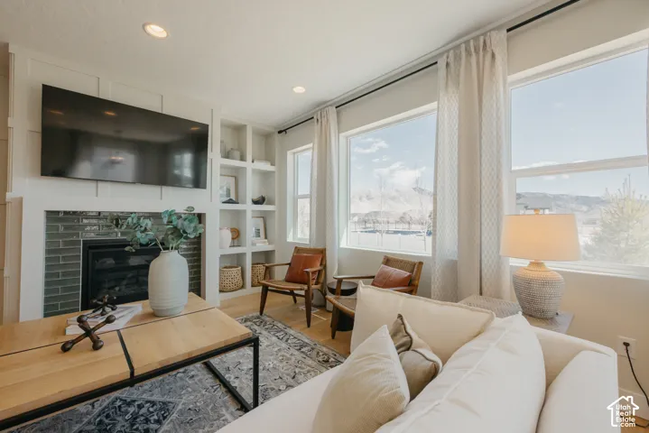 Fireplace featuring a glossy subway tile surround, custom built-in shelving with board and batten detailing, recessed lighting, and large windows with mountain scenery