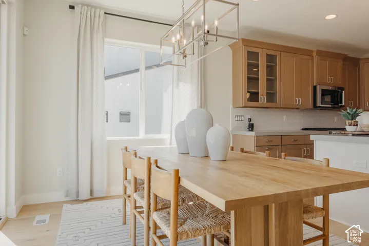 Kitchen featuring light wood cabinetry, subway tile backsplash, recessed lighting, and a linear metal chandelier