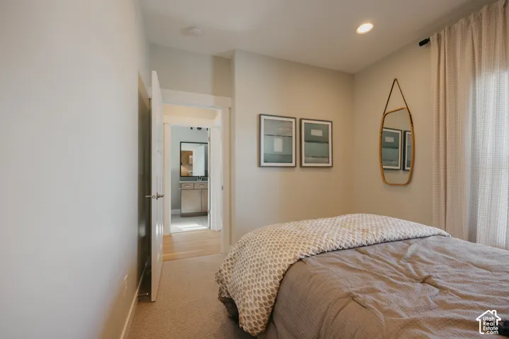 Neutral-toned interior space featuring light-colored wall-to-wall carpeting, recessed ceiling lighting, and a six-panel interior door