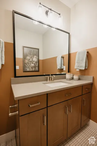 Vanity featuring wood-finish cabinetry, a solid surface countertop, an undermount sink, a framed mirror, and a three-light fixture