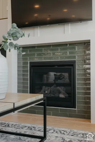 Fireplace featuring a glossy green subway tile surround, integrated hearth, and white board-and-batten detailing