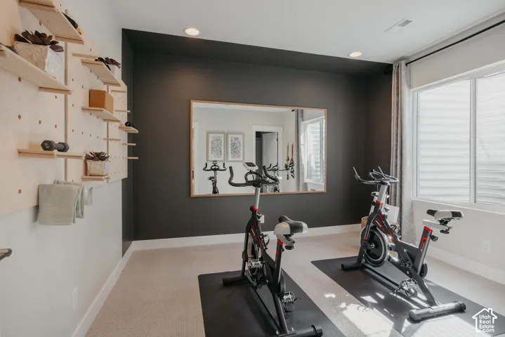 Room featuring an accent wall, wall-mounted light-wood pegboard shelving, large rectangular mirror with a wood frame, recessed lighting, and a window with horizontal blinds