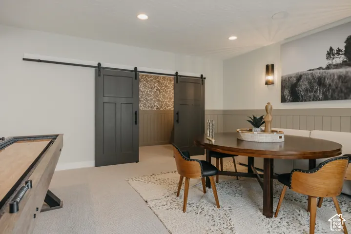 Dark charcoal sliding barn doors with matte black hardware, vertical wainscoting, recessed ceiling lighting, and a wall-mounted light fixture