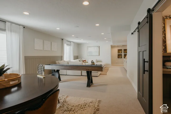 Open-concept room featuring recessed lighting, paneled wainscoting, and a sliding barn door with matte black hardware