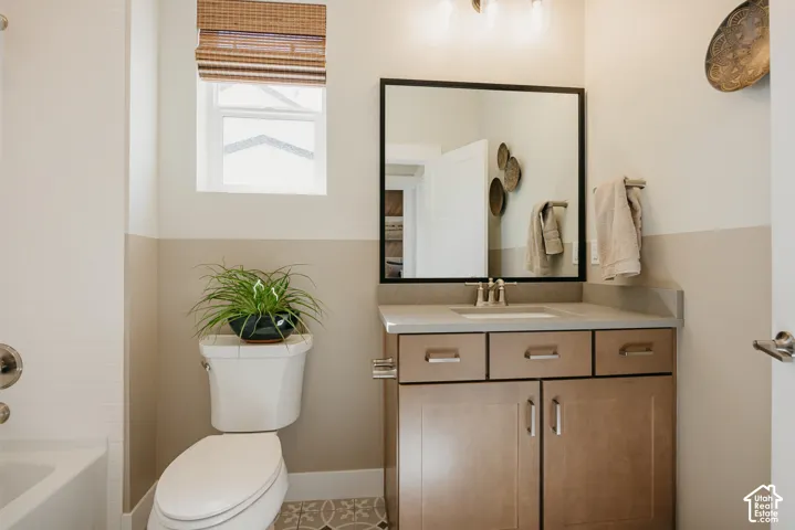 Bathroom vanity with a stone-composite countertop, undermount sink, shaker-style cabinetry, framed vanity mirror, and patterned floor tile