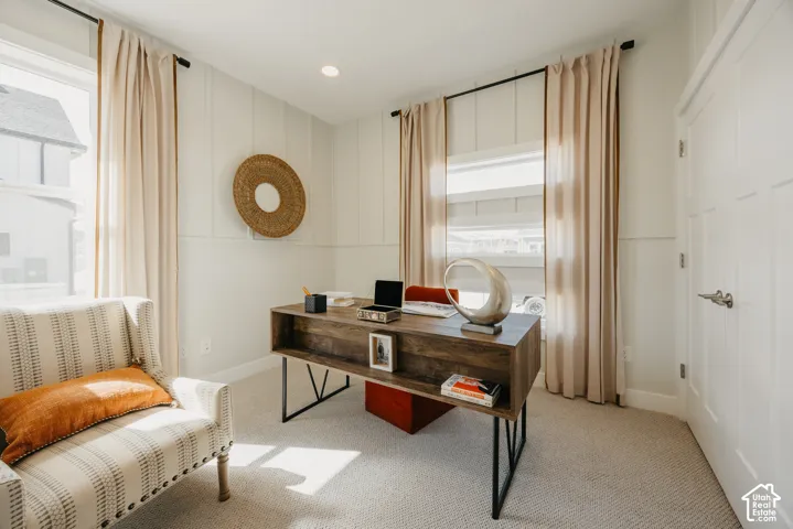 Room featuring vertical wall paneling, neutral carpeting, recessed lighting, and a multi-panel door with brushed metal hardware