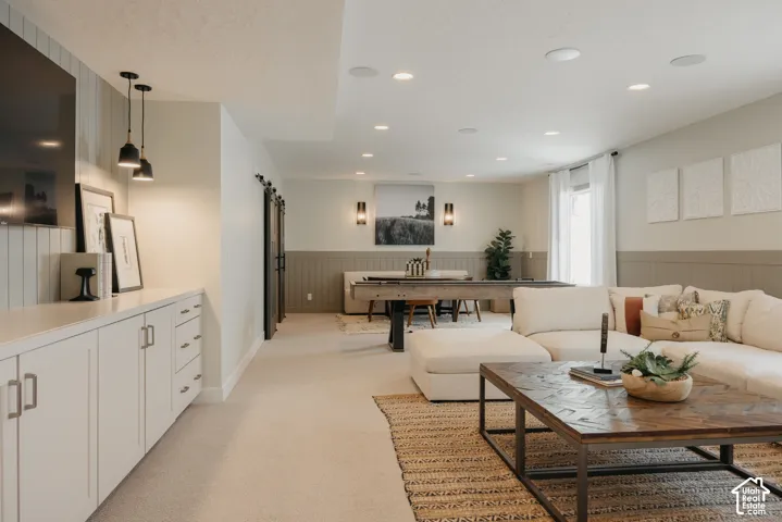 Built-in cabinetry with stone countertop, recessed ceiling lighting, wall-mounted light fixtures, board and batten wall treatment, and sliding barn-style doors