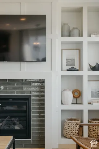 Fireplace featuring a multi-toned, high-gloss rectangular tile surround, grid-pattern wall millwork, and custom floor-to-ceiling built-in shelving