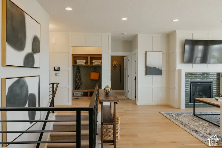 Interior featuring board-and-batten wall detailing, wood-finish flooring, recessed lighting, a fireplace with a ceramic tile surround, and built-in mudroom cabinetry