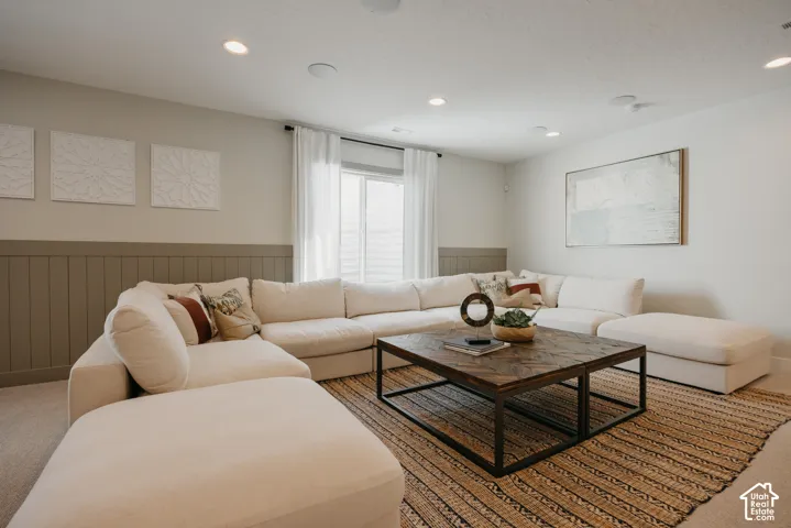 Living area featuring neutral wall paint, horizontal wainscoting, recessed lighting, and a window with integrated curtain rod hardware