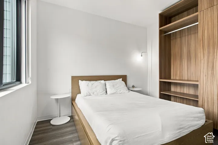 Built-in wood-finish cabinetry featuring open shelving and a hanging rod, integrated wood-finish platform frame, and wood-finish flooring
