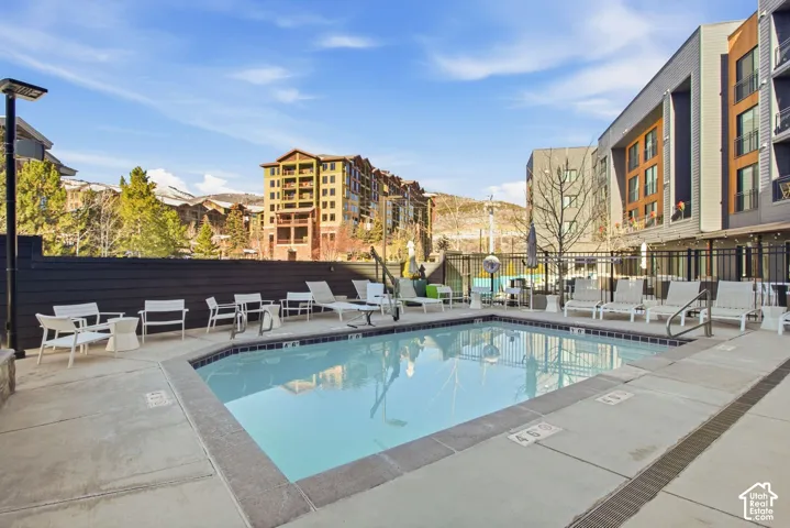 Outdoor swimming pool featuring a concrete deck and dark horizontal wood-plank perimeter fencing