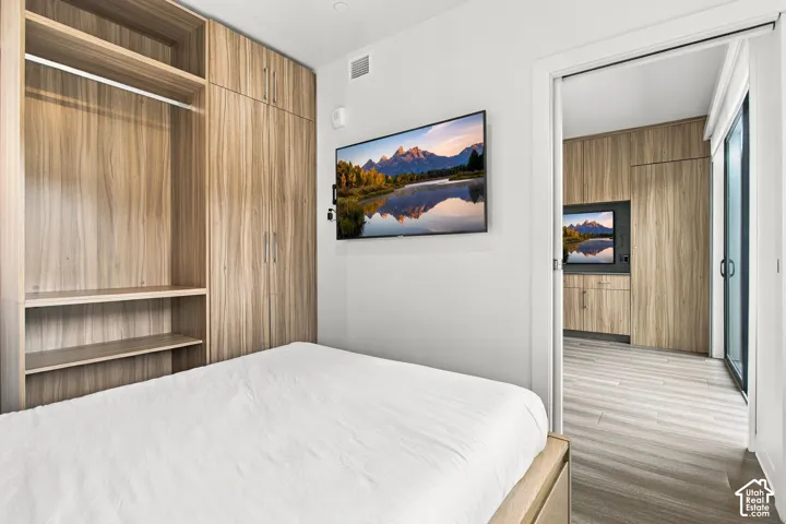 Floor-to-ceiling wood-finish cabinetry with integrated shelving and hanging rods, wood-finish flooring, and recessed ceiling lighting