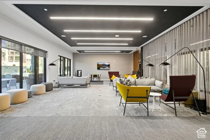 Tray ceiling with recessed linear lighting, floor-to-ceiling glass panel walls, and carpeted flooring