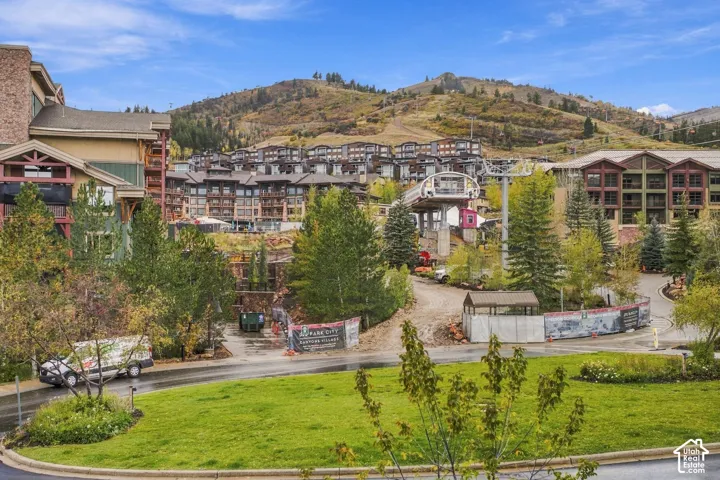 Mountain landscape featuring multi-story residential architecture with stone and wood-finish siding, surrounding evergreen trees, and proximity to a ski lift infrastructure