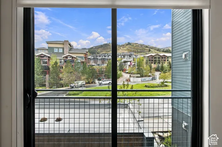 Sliding glass door with black frame and integrated metal mesh railing, showcasing a mountain backdrop and surrounding landscape