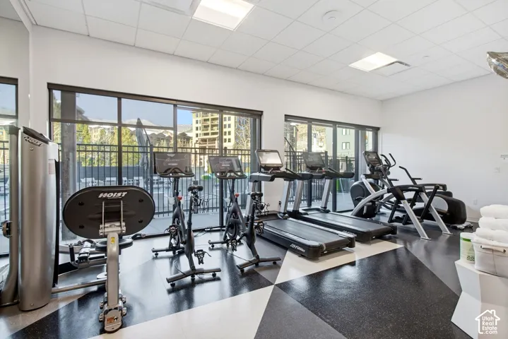 Fitness facility featuring geometric rubber flooring, floor-to-ceiling windows, and recessed ceiling lighting