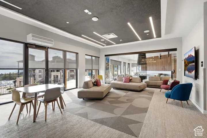 Open-concept common area featuring high-contrast tray ceilings with integrated linear LED lighting, expansive floor-to-ceiling windows, and wall-mounted ductless climate control