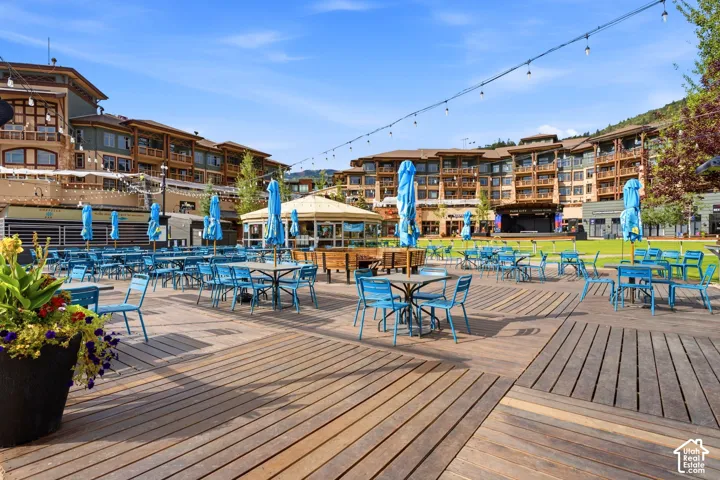 Expansive wood-plank patio featuring overhead string lighting and mountain scenery