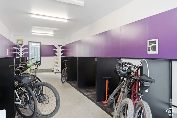 Bicycle storage area featuring dedicated partitioned stalls, concrete flooring, and overhead LED lighting