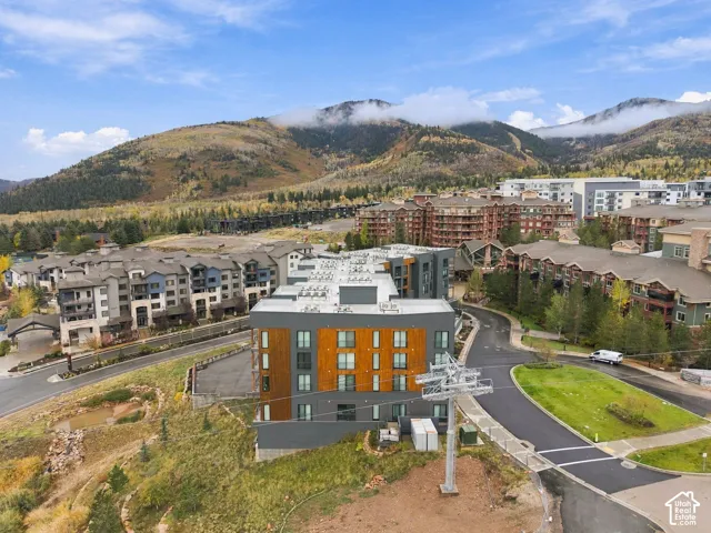 Multi-story residential building featuring wood-finish siding, dark charcoal architectural accents, and expansive mountain terrain backdrop