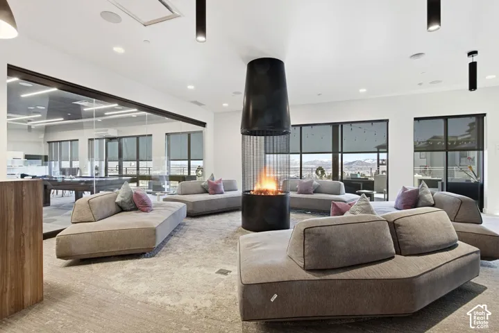 Suspended cylindrical fireplace with integrated mesh screen, floor-to-ceiling glass wall partitions, large-format window groupings, recessed ceiling lighting, and cylindrical pendant fixtures