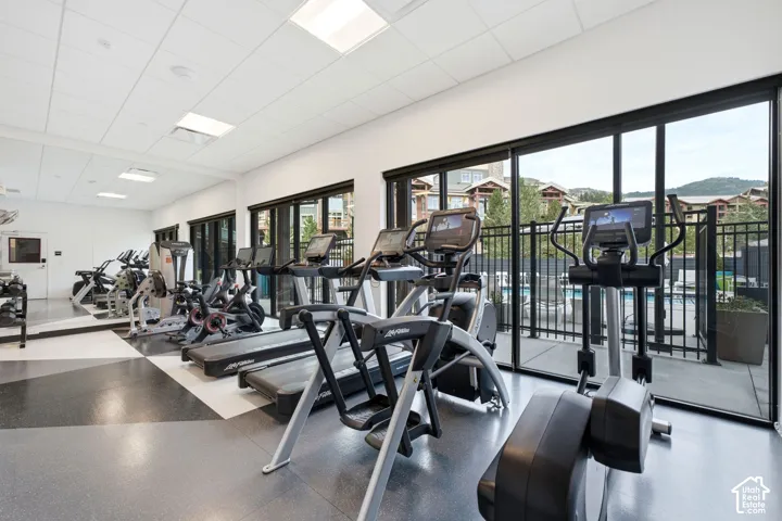 Fitness center featuring mirrored walls, recessed ceiling lighting, multi-toned geometric flooring, and floor-to-ceiling sliding glass doors