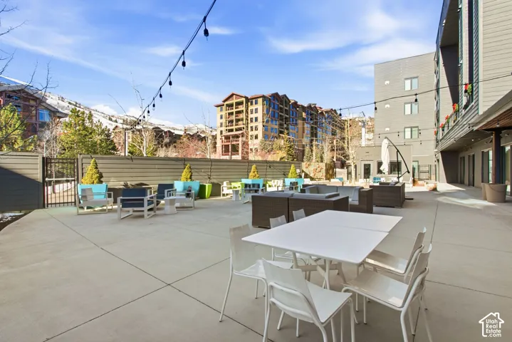 Spacious concrete patio featuring perimeter privacy fencing, string lighting, and mountain scenery