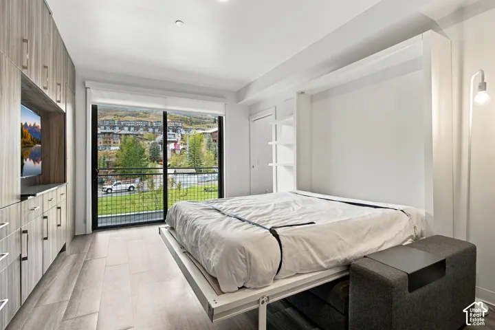 Built-in floor-to-ceiling cabinetry with wood-finish doors, integrated wall-mounted bed system, wood-finish flooring, and large-format sliding glass door with a mountain backdrop