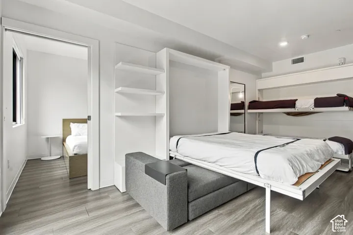 Custom white built-in shelving, integrated wall-mounted bunk unit, and wood-finish flooring